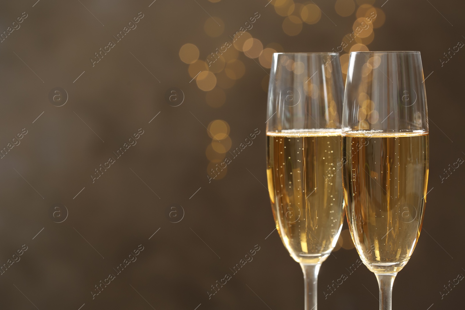 Photo of Glasses of champagne against blurred lights, closeup. Space for text