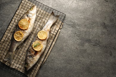 Photo of Baked fish with lemon on grey textured table, top view. Space for text