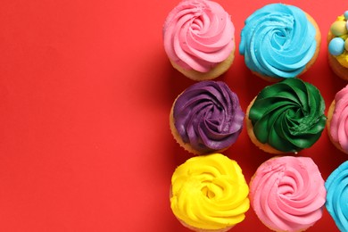 Photo of Delicious cupcakes with bright cream on red background, flat lay. Space for text