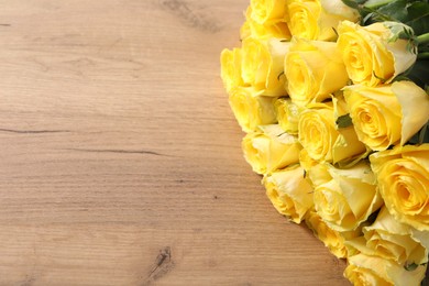 Beautiful bouquet of yellow roses on wooden table, above view. Space for text