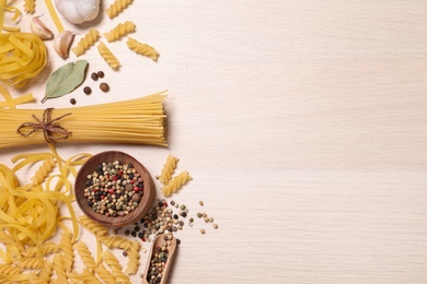 Photo of Flat lay composition with different types of pasta on light wooden table, space or text