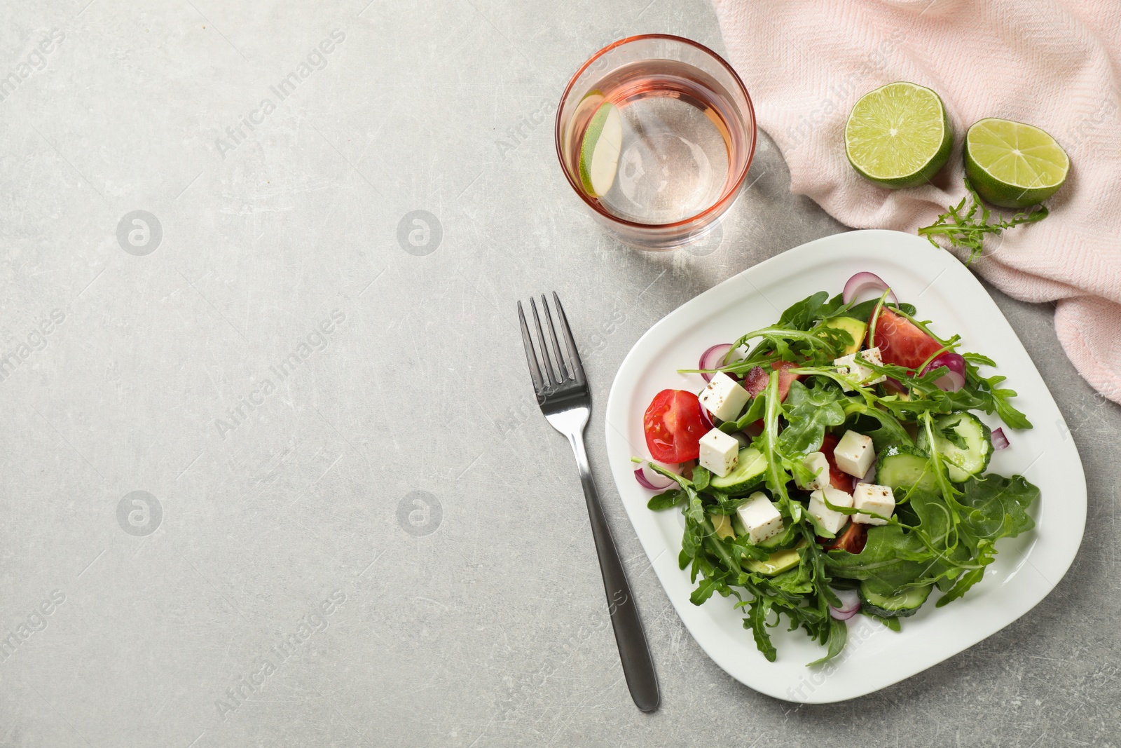 Photo of Delicious salad with feta cheese, arugula and vegetables on grey table, flat lay. Space for text