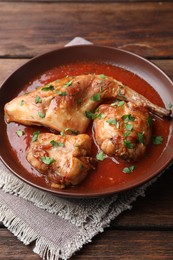 Photo of Tasty cooked rabbit meat with sauce and parsley on wooden table