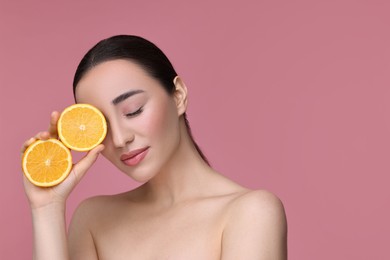 Photo of Beautiful young woman with pieces of orange on pink background. Space for text