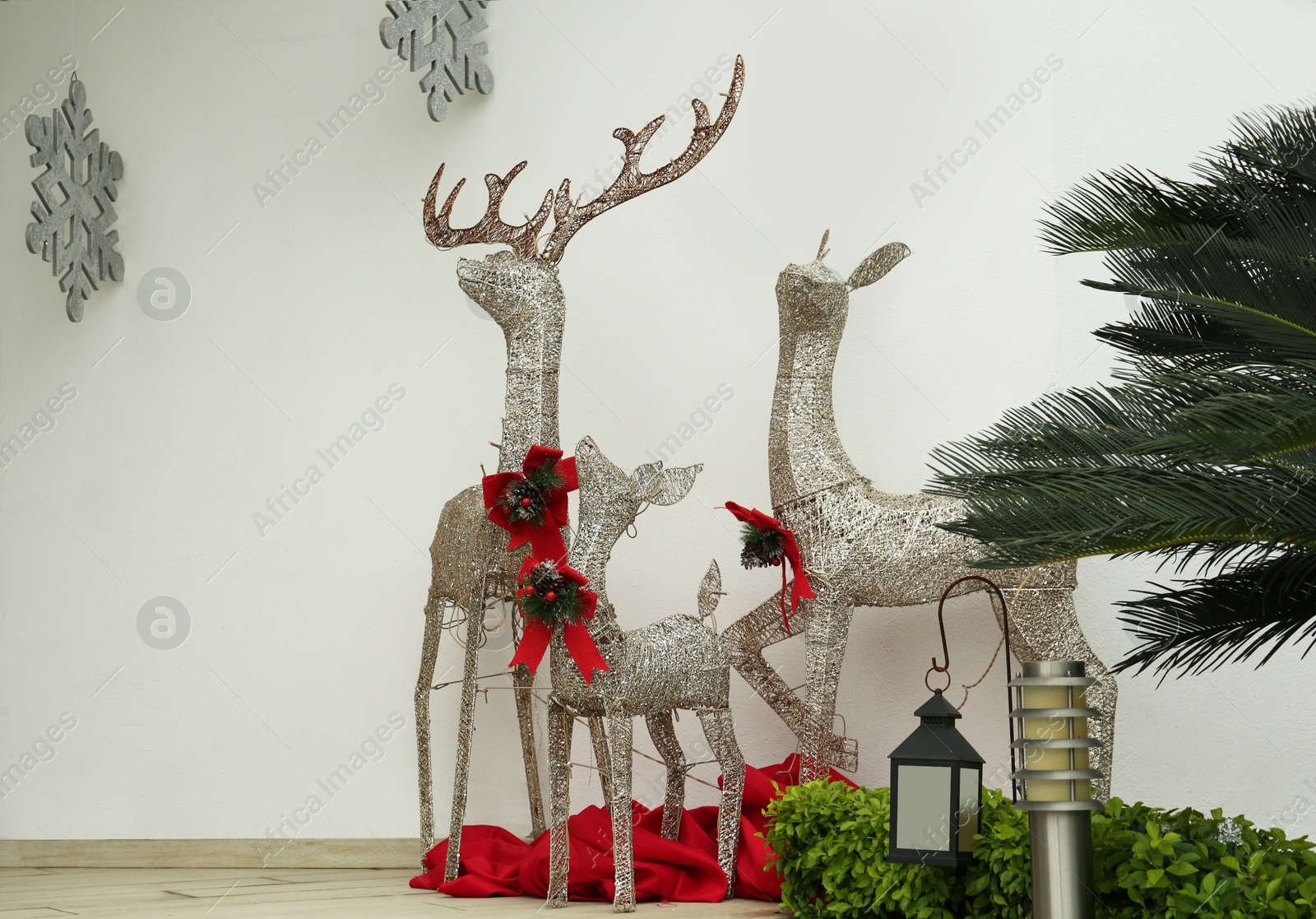 Photo of Beautiful Christmas deers near palm tree outdoors. Festive street decorations