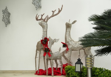 Beautiful Christmas deers near palm tree outdoors. Festive street decorations