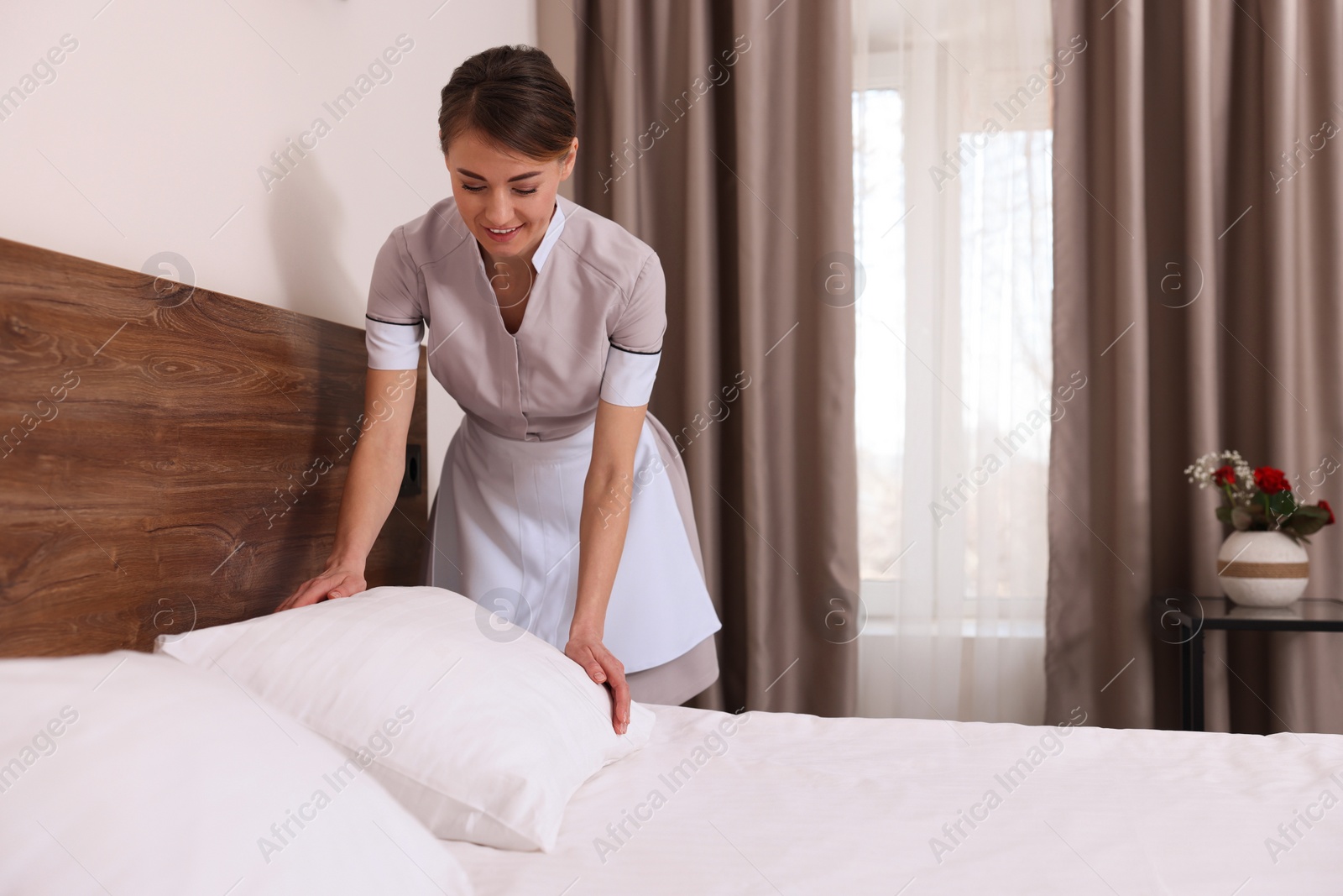 Photo of Beautiful chambermaid making bed in hotel room