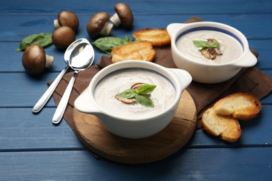 Photo of Fresh homemade mushroom soup served on blue wooden table