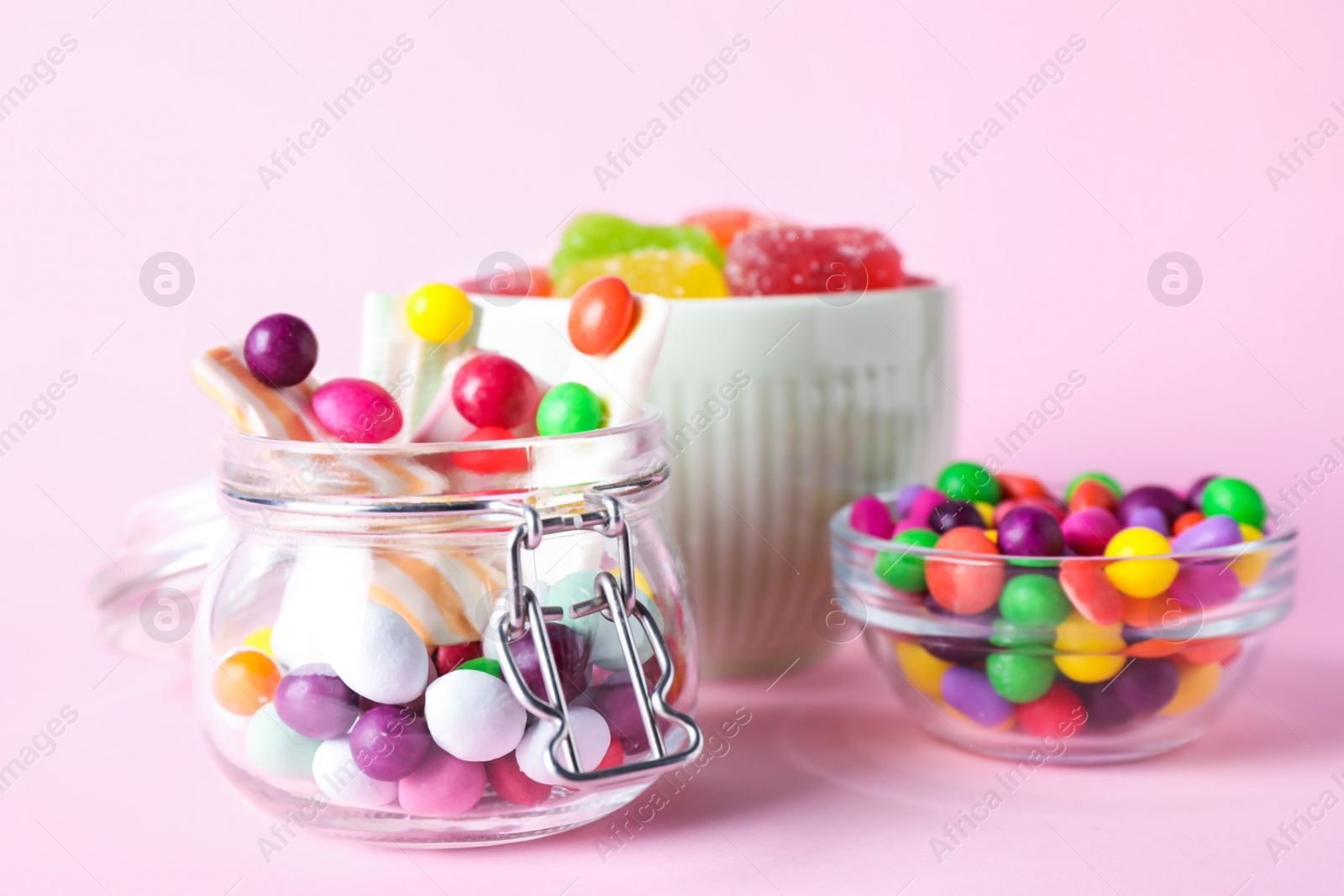 Photo of Many different yummy candies on pink background