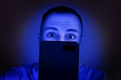 Internet addiction. Man using smartphone at night. Toned in blue
