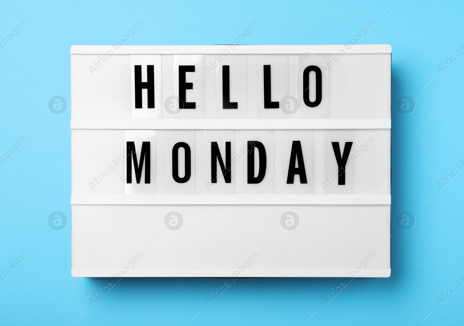 Photo of Light box with message Hello Monday on turquoise background, top view