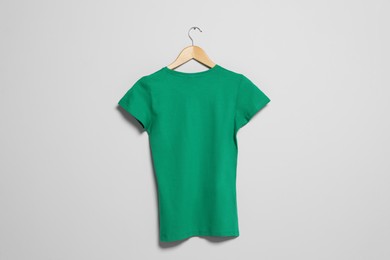 Hanger with green t-shirt on light wall. Mockup for design
