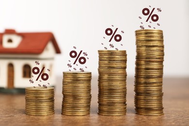 Mortgage rate. Stacked coins, percent signs and model of house