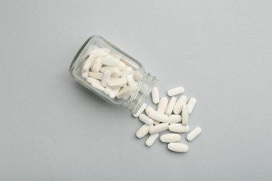 Photo of Vitamin pills and bottle on grey background, top view