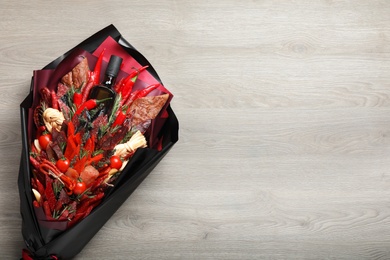 Photo of Beautiful edible bouquet with meat, cheese and vegetables on wooden table, top view. Space for text