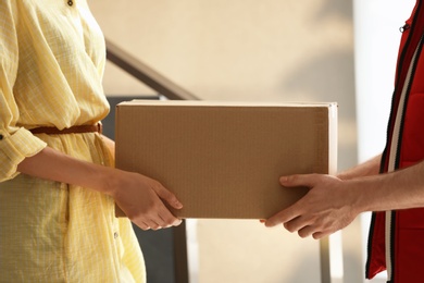 Photo of Woman receiving parcel from deliveryman on blurred background, closeup. Space for text