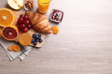 Delicious breakfast with croissant on wooden table, flat lay. Space for text