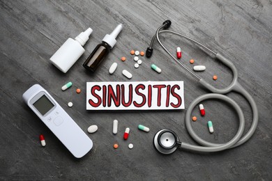Photo of Card with word SINUSITIS, stethoscope, non-contact thermometer and different drugs on grey stone background, flat lay
