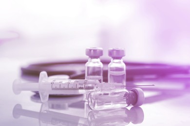 Image of Syringe and glass vials on mirror surface, closeup. Color toned