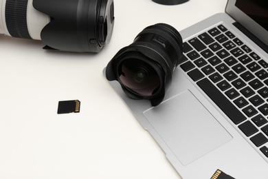 Laptop and professional photographer's equipment on white table