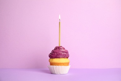 Birthday cupcake with candle on violet background