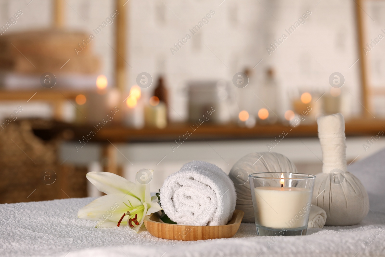 Photo of Spa composition with burning candle and herbal bags on massage table in wellness center