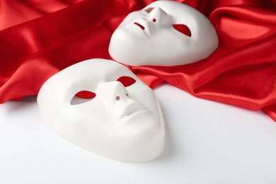 Theatre masks and red fabric on white background