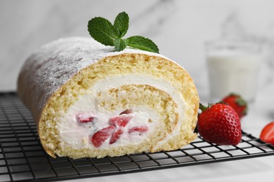Photo of Delicious sponge cake roll with strawberries and cream on white table, closeup