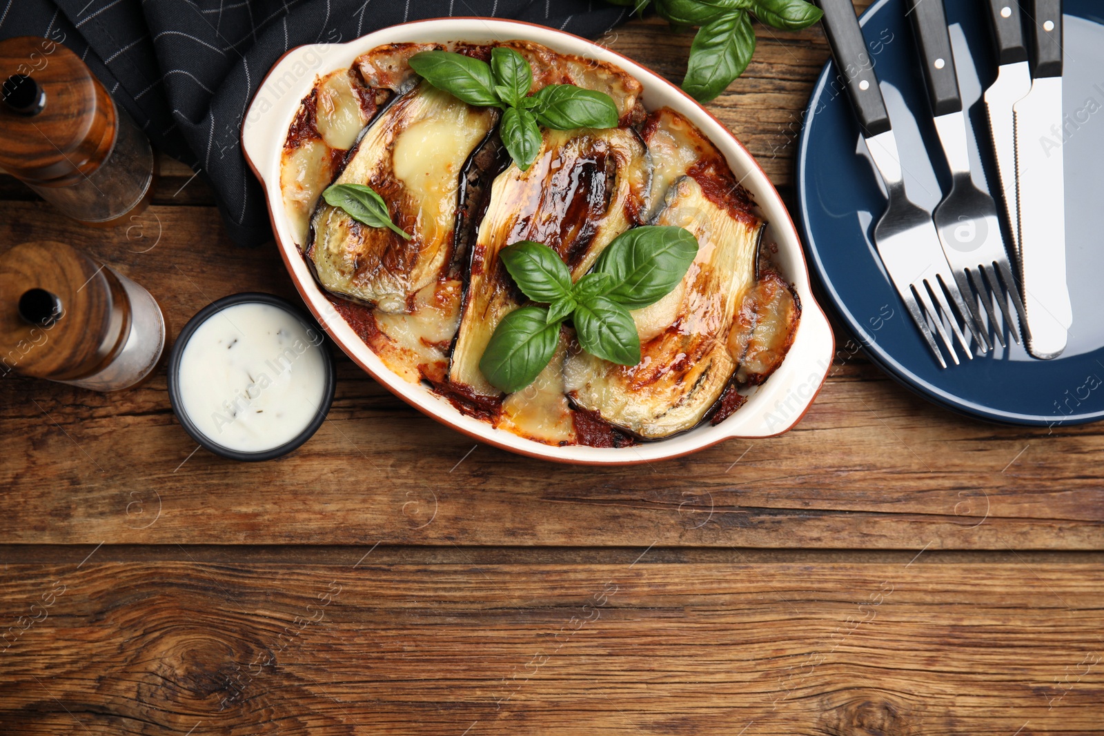 Photo of Delicious eggplant lasagna in baking dish on wooden table, flat lay. Space for text