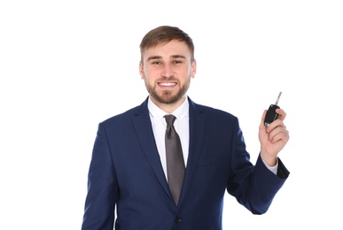 Happy young businessman with car key on white background