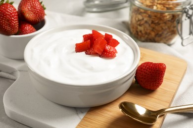 Photo of Delicious yogurt served with strawberries on grey marble table