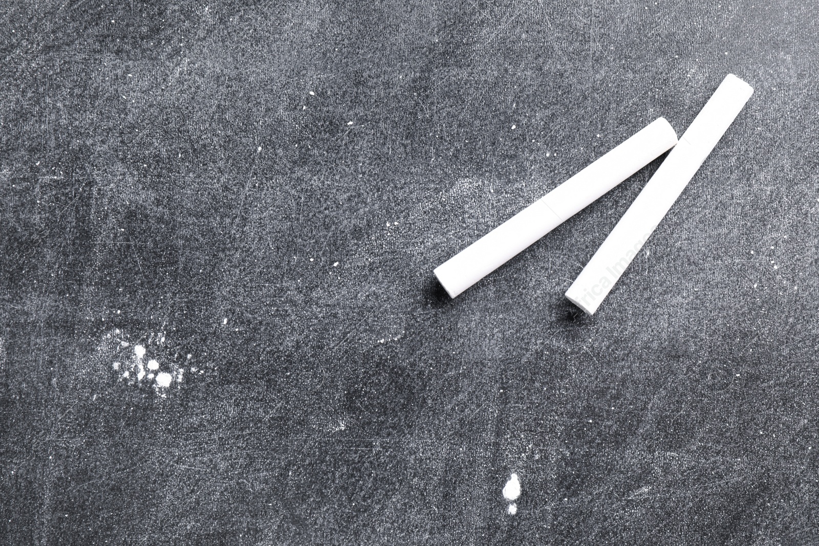 Photo of Pieces of white chalk on blackboard, flat lay. Space for text