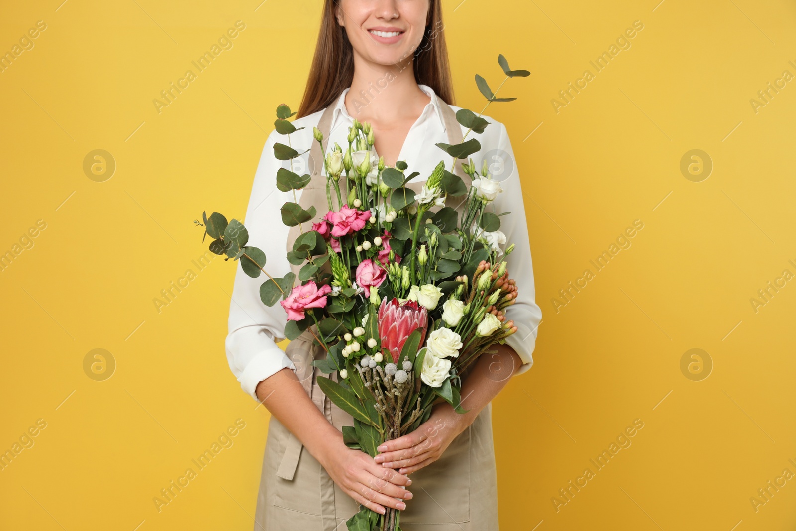 Photo of Florist with beautiful bouquet on yellow background, closeup