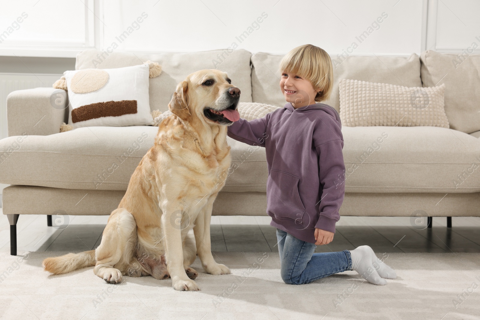 Photo of Cute little child with Golden Retriever on floor at home. Adorable pet