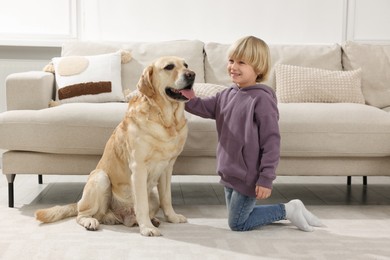 Photo of Cute little child with Golden Retriever on floor at home. Adorable pet