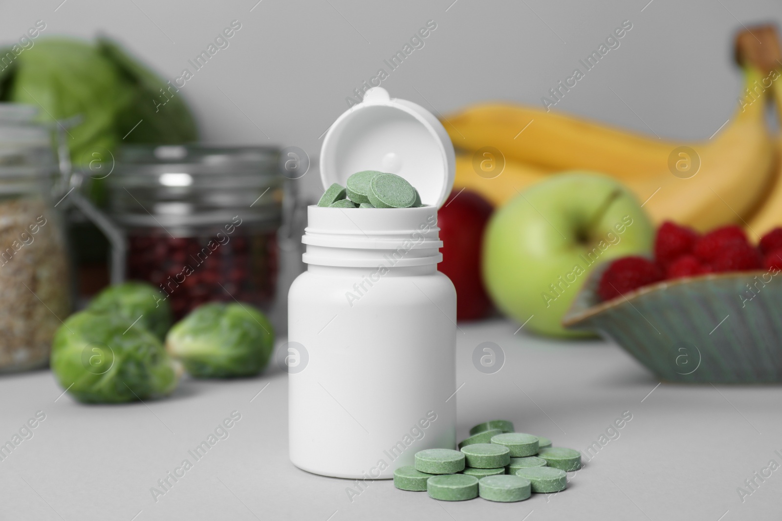 Photo of Bottle of prebiotic pills and food on grey table