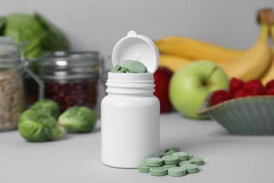 Photo of Bottle of prebiotic pills and food on grey table