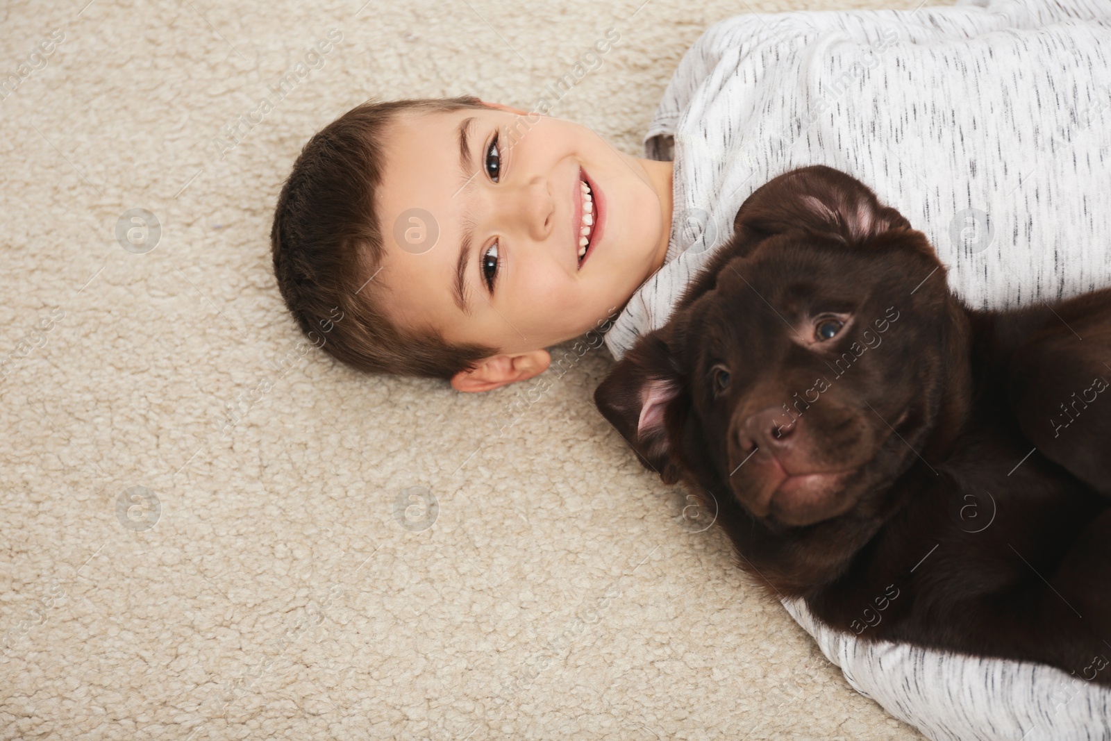 Photo of Little boy with dog lying on floor, top view