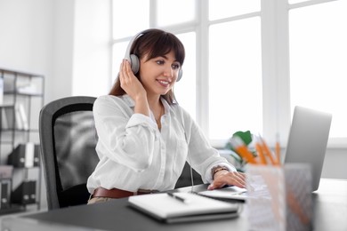 Woman in headphones watching webinar at table in office