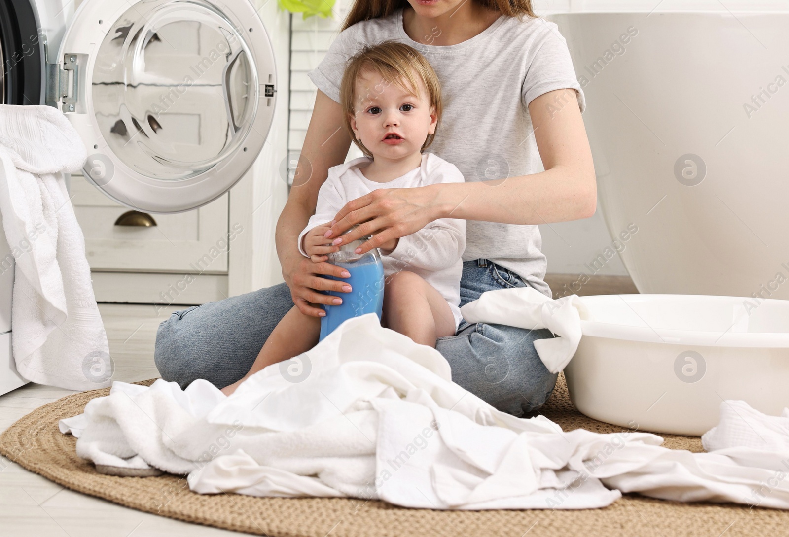 Photo of Mother with her daughter washing baby clothes in bathroom