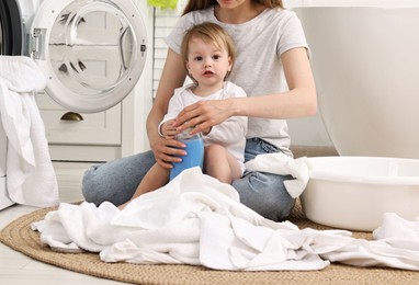 Mother with her daughter washing baby clothes in bathroom