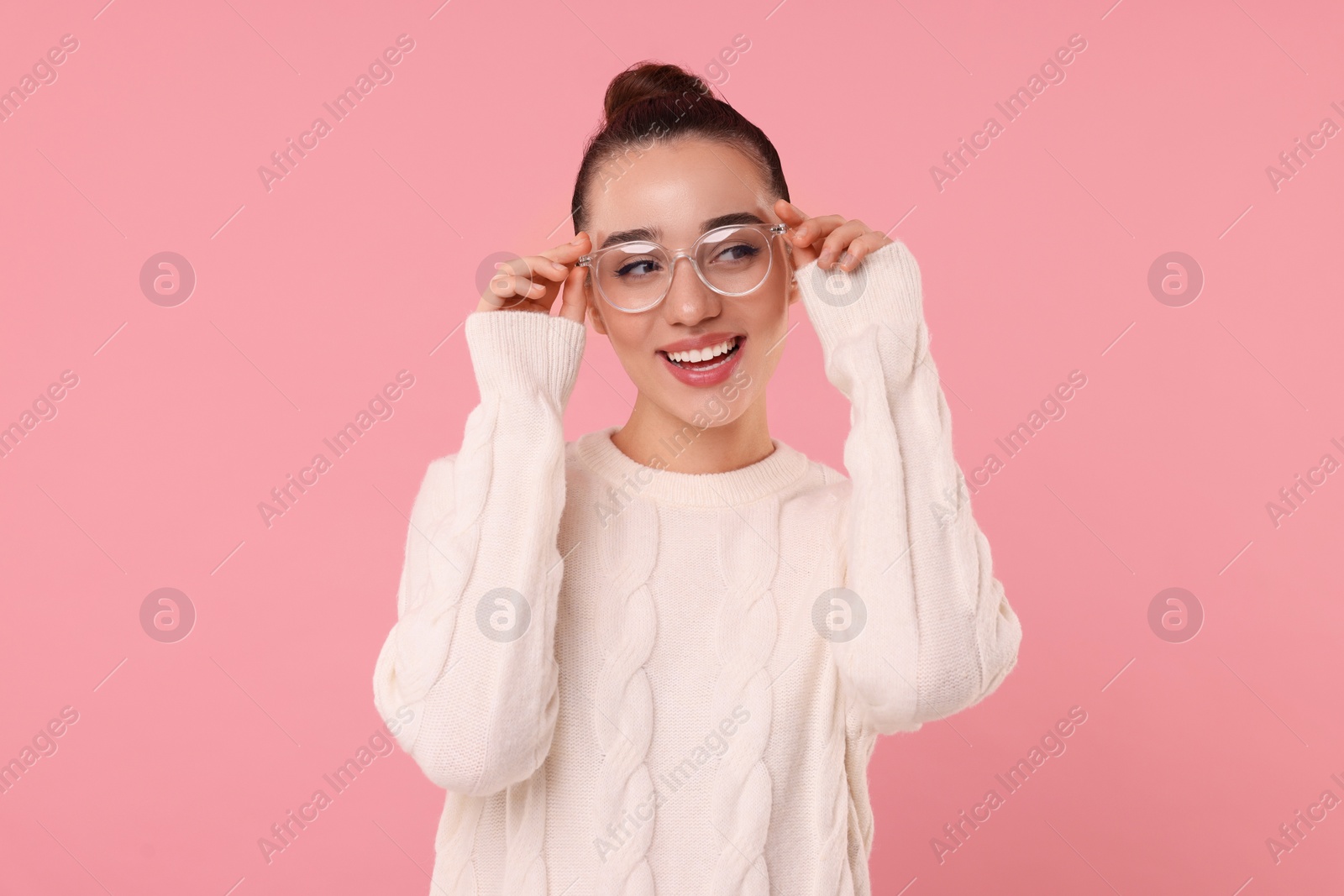 Photo of Beautiful young woman in stylish warm sweater on pink background