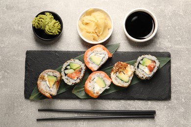 Delicious sushi rolls on light grey table, flat lay