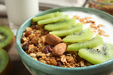 Tasty granola with yogurt and sliced kiwi for breakfast on table, closeup