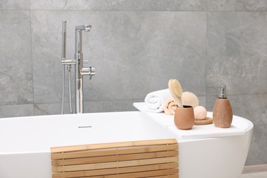 Different personal care products and accessories on bath tub in bathroom