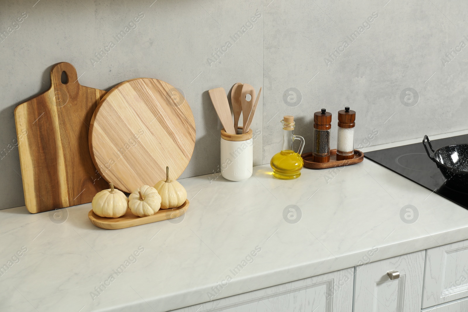 Photo of Wooden cutting boards and other cooking utensils on white countertop in kitchen