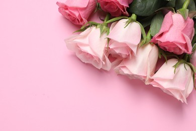 Photo of Beautiful roses on light pink background, top view. Space for text