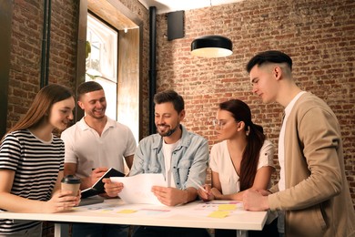 Photo of Team of employees working together in office