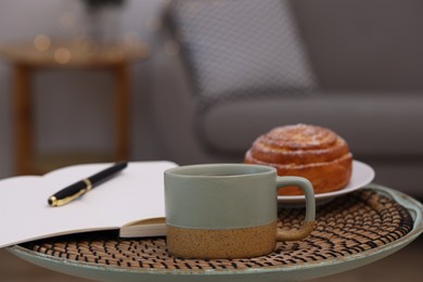Cup of drink, pastry and notebook on coffee table indoors