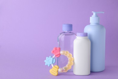 Photo of Different skin care products for baby and rattle on violet background, space for text
